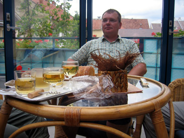 Dirk erwartet uns im Wintergarten unseres Hotels Szent Jnos mit ungarischem Chardonnay-Wein und Krts-kalcs (= Baumstriezelkuchen)